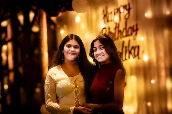 Two friends share a knowing smile at a birthday party