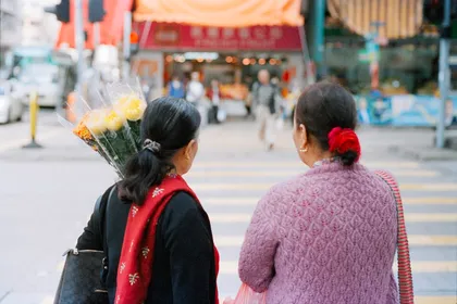 Two people walking down a city street carrying flowers